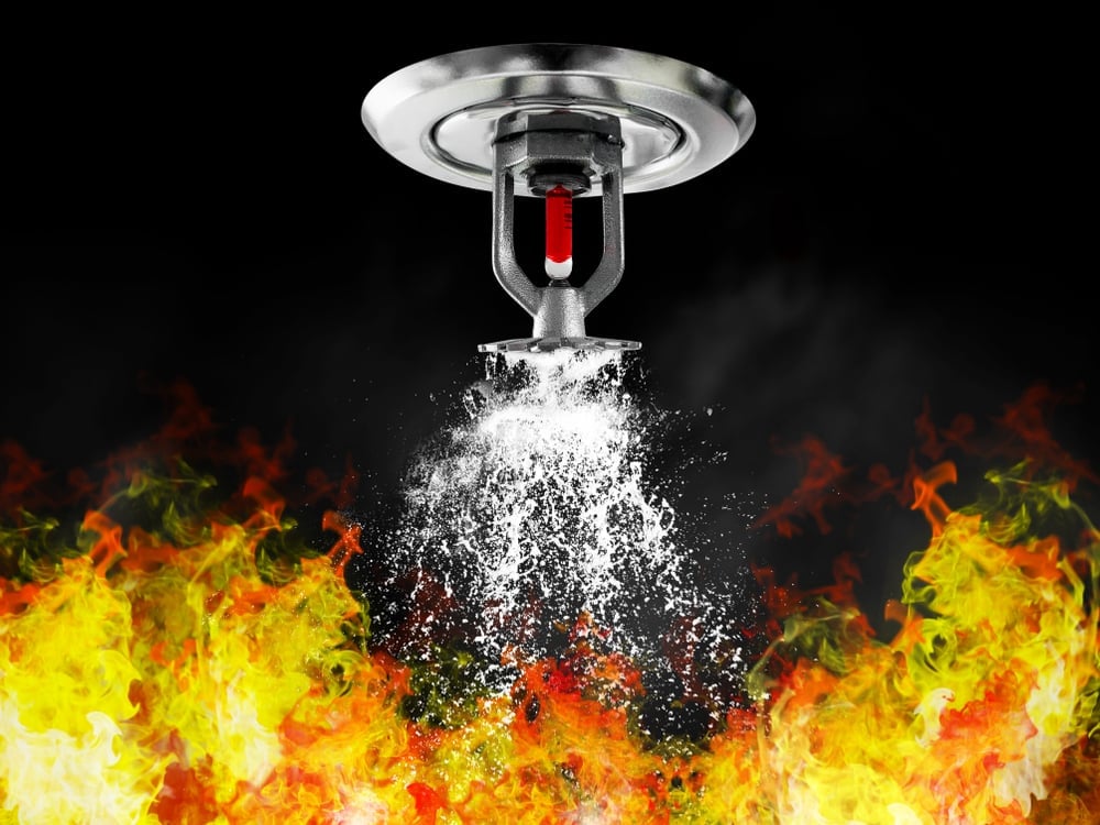 Fire sprinkler spraying water over flames