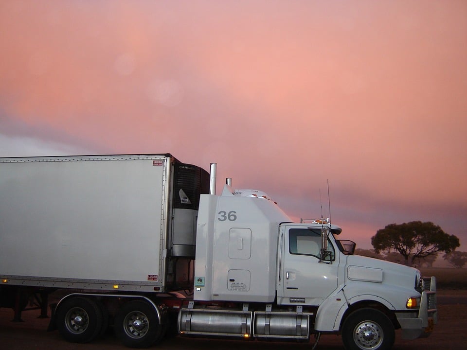 White semi-truck with refrigerated trailer at sunset