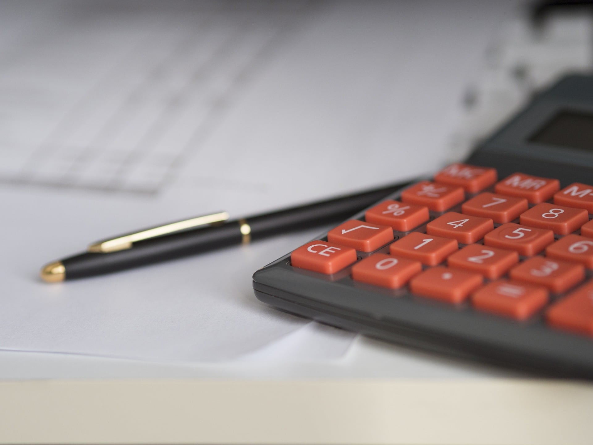 Calculator, pen and paperwork on office desk