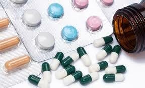 Assorted pills and capsules spilling from bottle