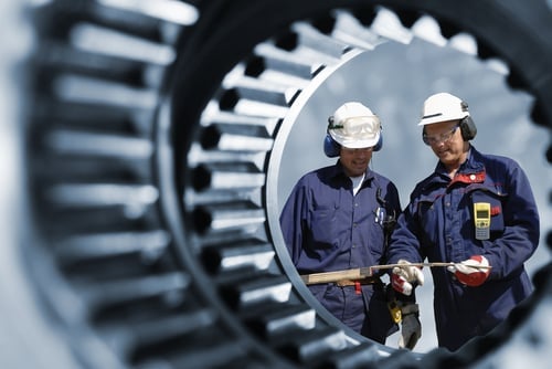 Engineers inspecting large industrial gear machinery