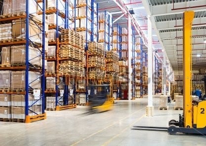 Forklift moving pallets in large warehouse