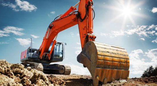 Orange excavator digging at sunny construction site