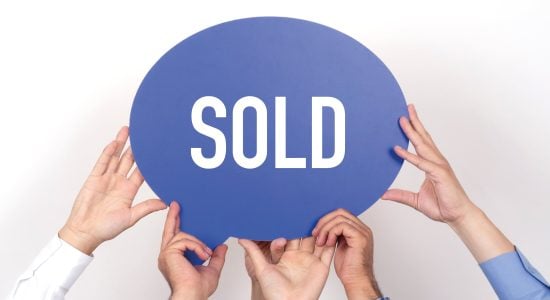 Hands holding blue speech bubble with SOLD text